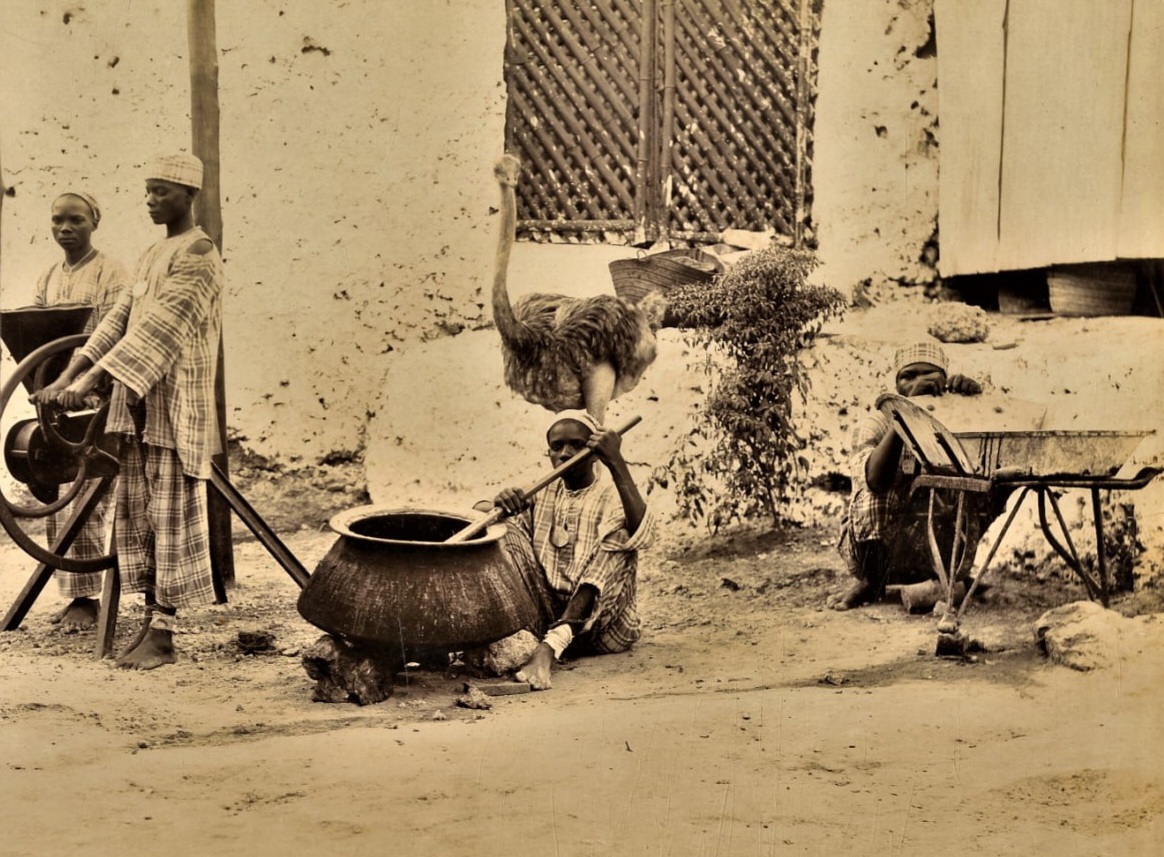 Personnes d’origine servile produisant du jus de canne à sucre dans une rue de Zanzibar, dans les années 1870. Chacune porte autour du cou le même insigne métallique numéroté, signe qui pourrait indiquer qu’elles avaient probablement été affranchies, récemment ou non. © Coutinho Brothers