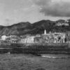 Vue de la façade maritime de la ville de Mtsamɗu, à Ndzuani, dominée en hauteur par sa citadelle, photographiée en 1952. © Pierre Coudert/ECPAD