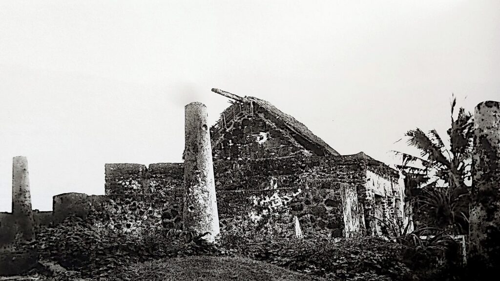 L’une des vieilles mosquées de Fumɓuni, accompagnée des tombeaux anciens des sultans du Mbadjini, dont certains se distinguent par des colonnes caractéristiques, réservées à ceux morts sur le trône. Photographie prise par le colon français Henri Pobéguin en mars 1898.