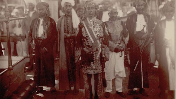 Au centre de l’image, le jeune prince Salim bin Abdallah de Ndzuani apparaît richement décoré. Il arbore quatre croix de l’Étoile de Ndzuani sur le côté gauche de sa veste ainsi qu’une grand-croix portée au cou. Il pose, en 1883, sur le pont d’un navire aux côtés d’une délégation de cinq dignitaires. © Smithsonian Institution